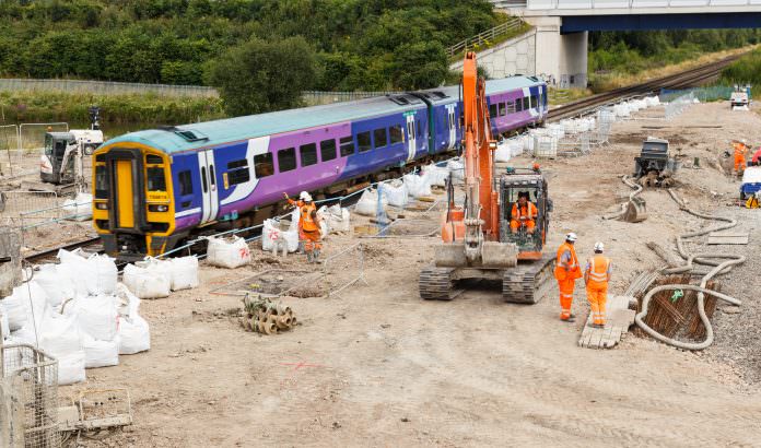 A train passes by construction workers on site next to a section of railway track. In Ilkeston. Credit: Jason Batterham/Shutterstock.